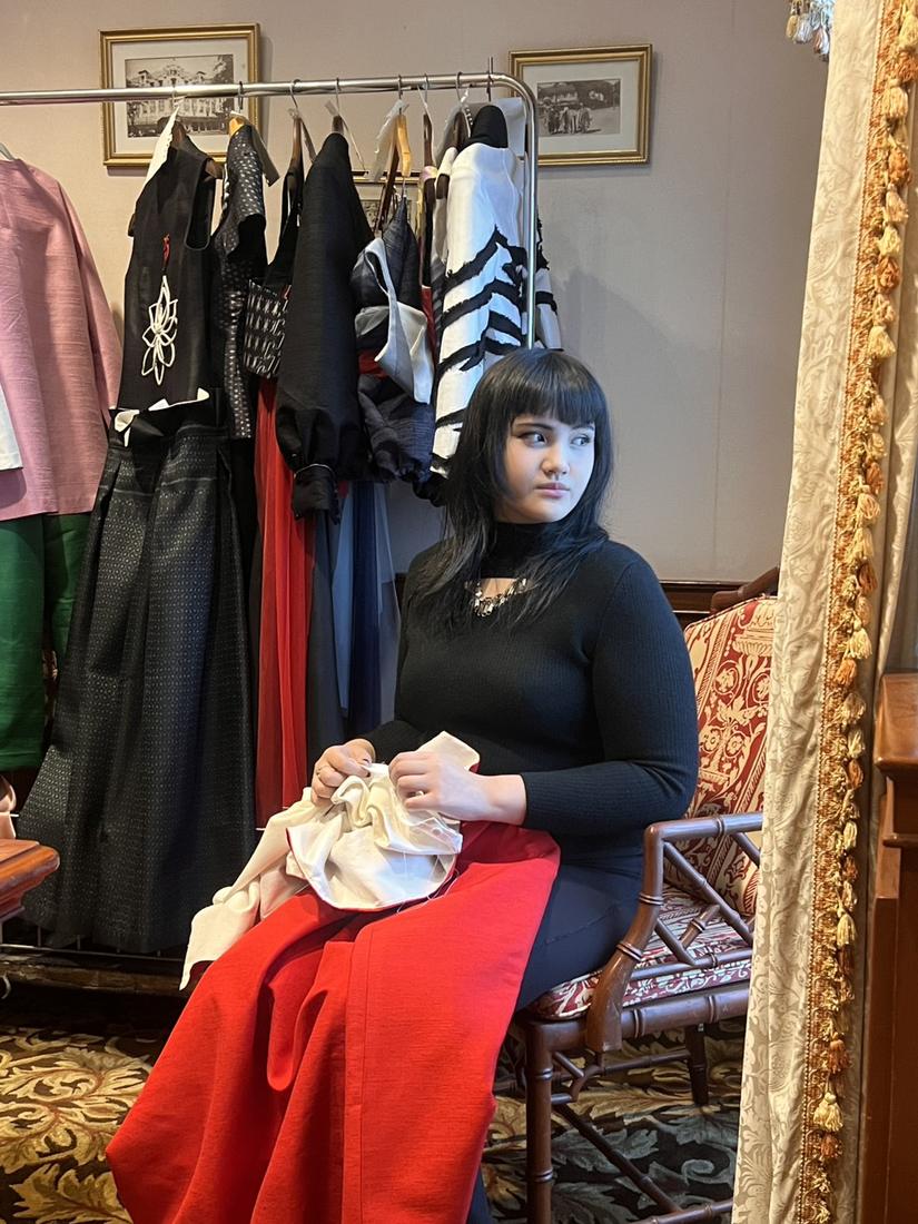 Mika seated beside a rack of the collection, holding silk fabric