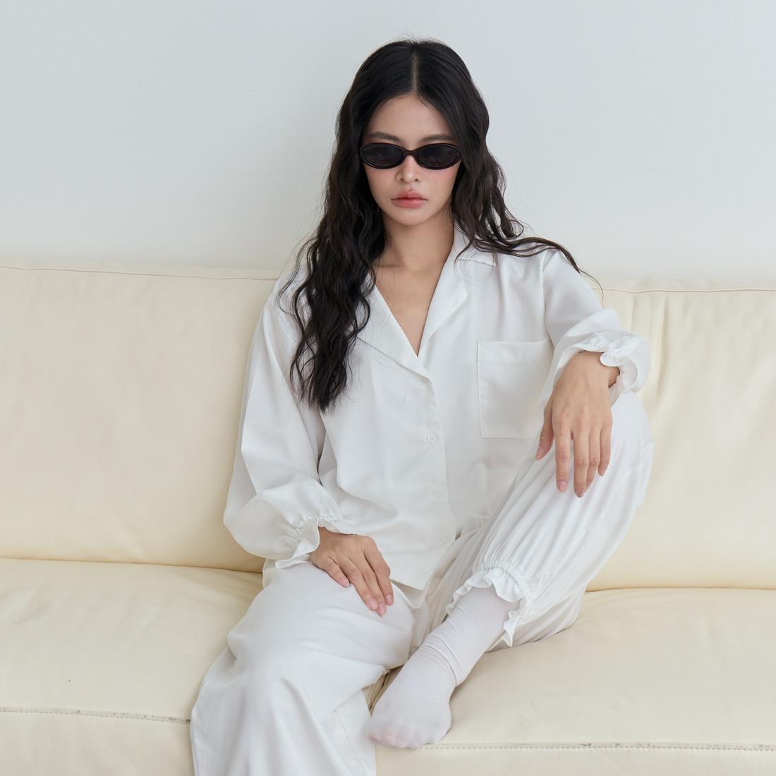 Model in a white Dreamwave pyjama set seated on a sofa