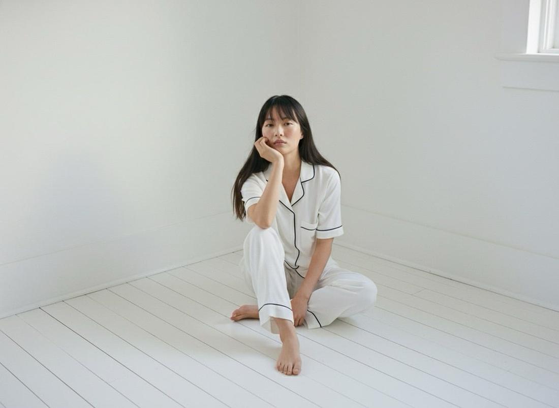 Model in white Dreamwave pyjamas sitting on a white floor