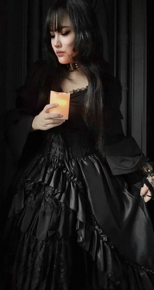 Mika in a black gothic gown holding a candle