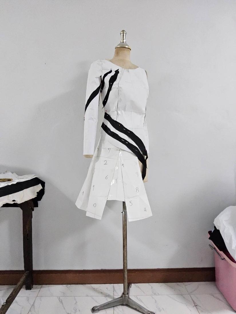 White dress with black stripe detailing on a dress form