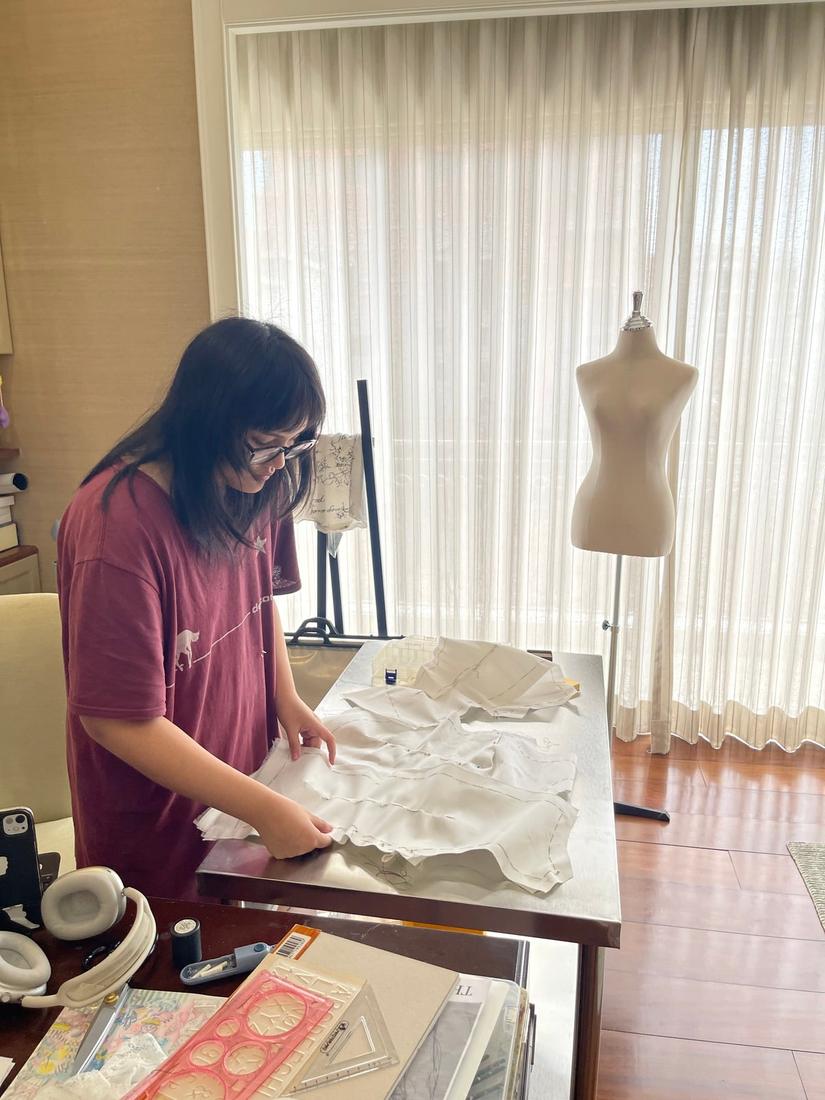 Mika cutting and sewing fabric in the studio