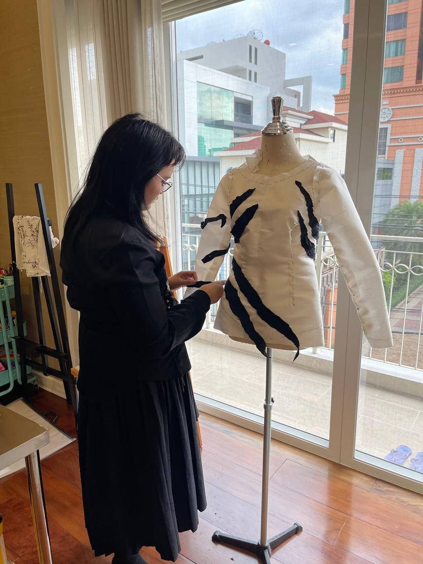 Mika fitting a white and black jacket on a dress form