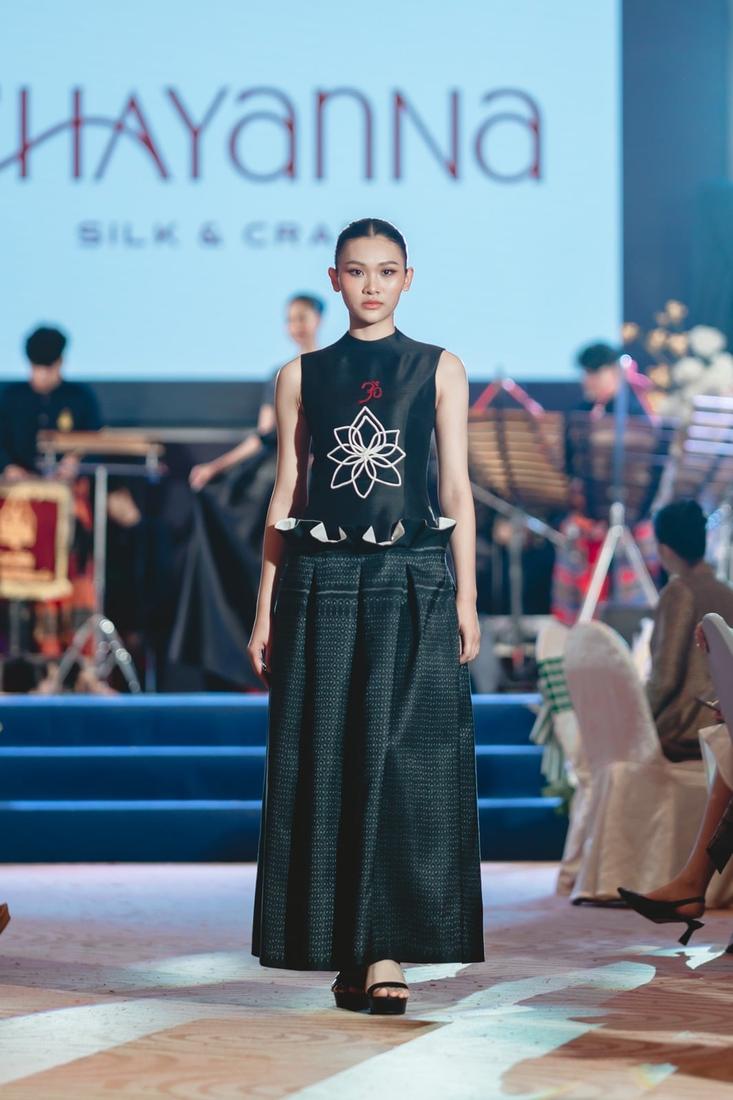 Model on the runway in a black embroidered top and long black skirt
